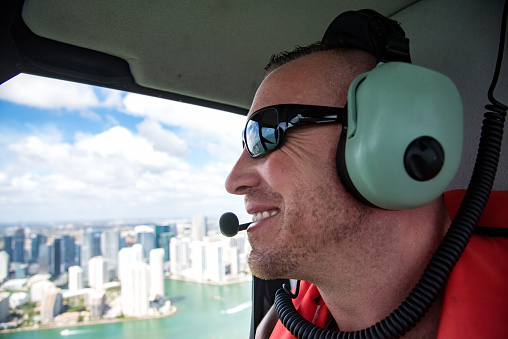 One mid 30s white male wearing a headset looking out at the skyline of Miami, Florida during a helicopter tour
