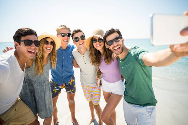 istock Cheerful young friends taking selfie at beach 676568256