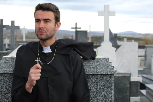 Priest performing an exorcism in a cemetery Priest performing an exorcism in a windy cemetery. christian social union photos stock pictures, royalty-free photos & images