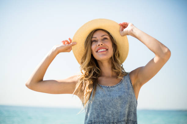 souriante jeune femme debout avec ciel - femmes dâge moyen photos et images de collection