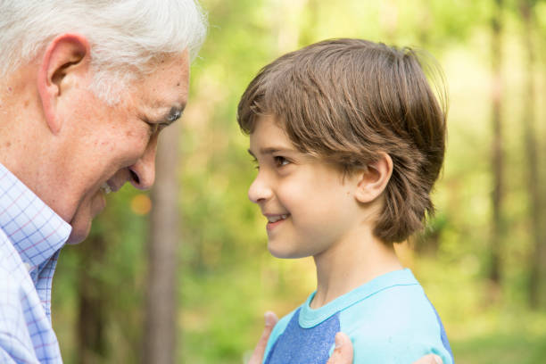 istock Grandfather and grandson face-to-face outdoors together. 676593520