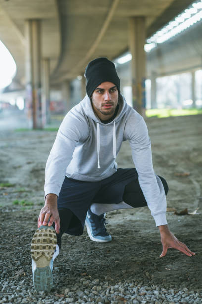istock Young man stretching his leg muscles under the bridge before running. 676595868