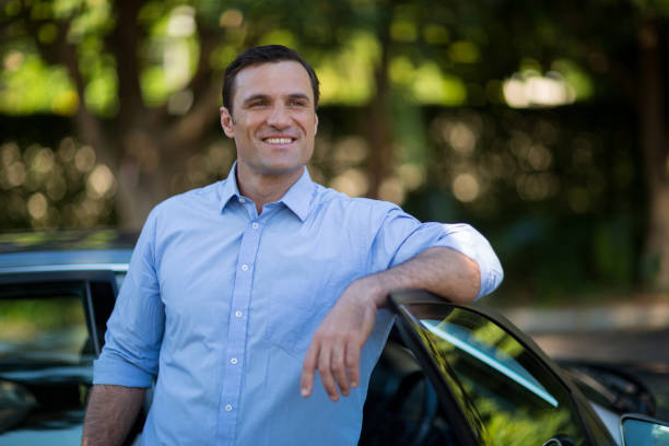 istock Smiling man leaning on car door 676596322
