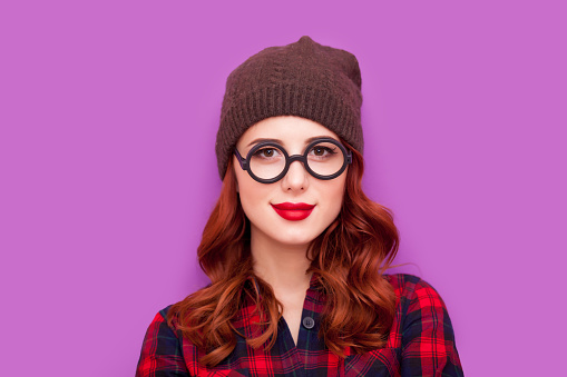 beautiful young woman standing in hipster glasses on the wonderful purple background