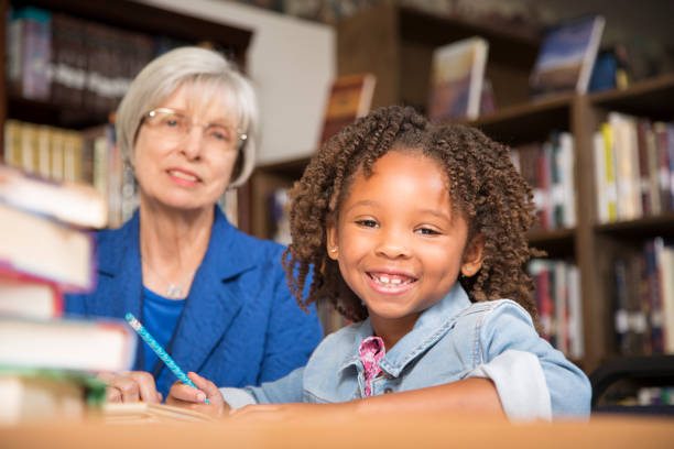 istock Teacher, mentor helps elementary-age schoolgirl with homework. 676647220