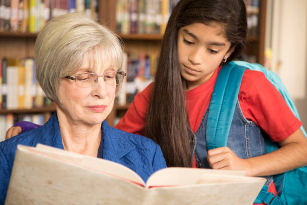 istock Teacher, librarian reads book to elementary student in library or classroom. 676652852