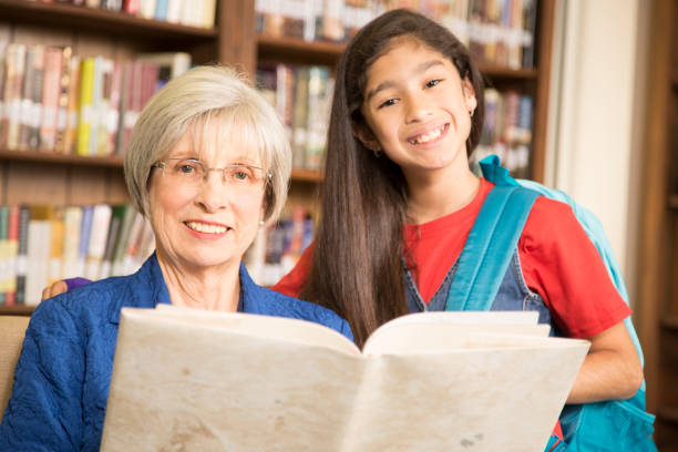 istock Teacher, librarian reads book to elementary student in library or classroom. 676658200