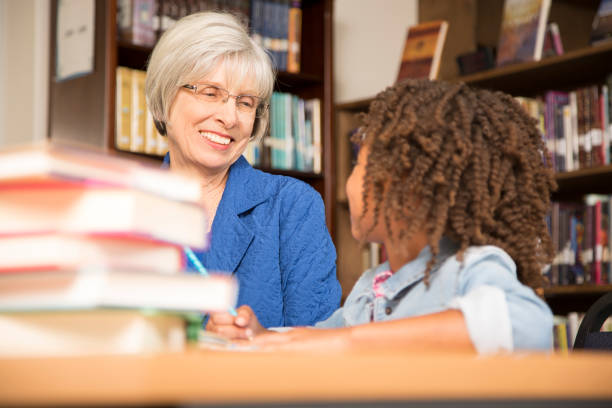 istock Teacher, mentor helps elementary-age schoolgirl with homework. 676679792