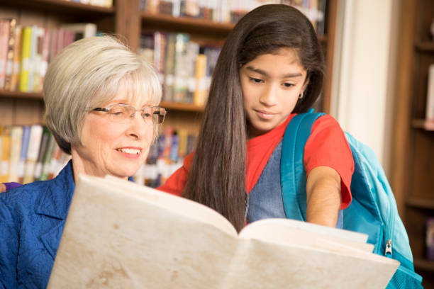 istock Teacher, librarian reads book to elementary student in library or classroom. 676694102