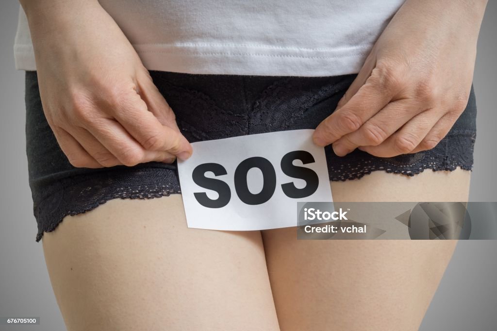 Vaginal or menstrual problems concept. Young woman holds paper with SOS above crotch. Vagina Stock Photo