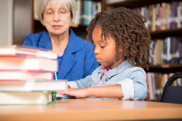 istock Teacher, mentor helps elementary-age schoolgirl with homework. 676713982