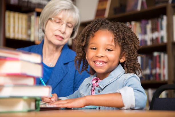 istock Teacher, mentor helps elementary-age schoolgirl with homework. 676714630