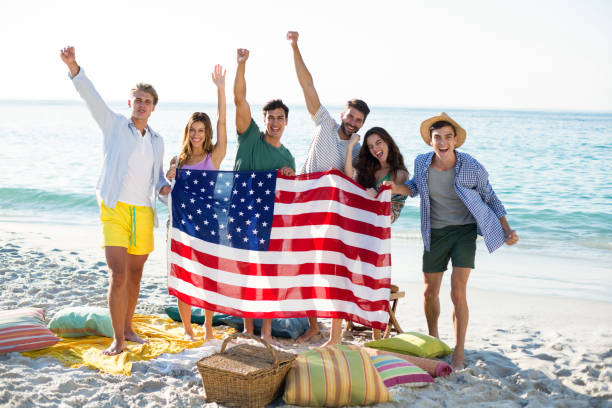 istock Friends holding American flag while standing on shore 676737468