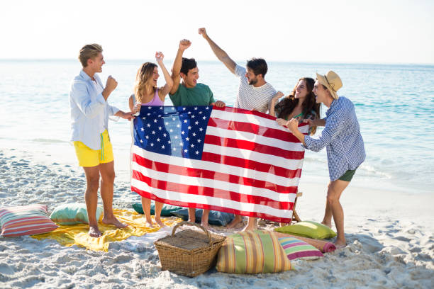 istock Friends holding American flag on shore at beach 676737726