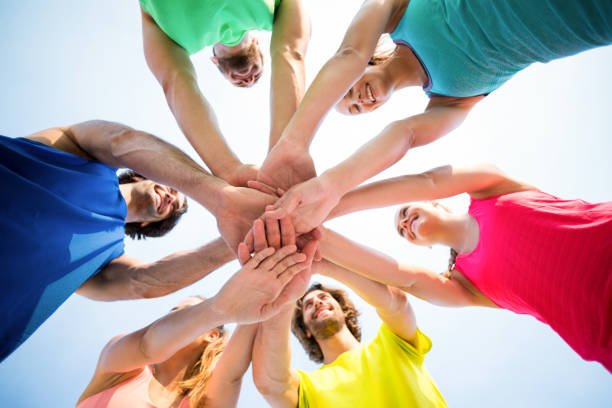 istock Friends standing with stacked hands against sky 676762086