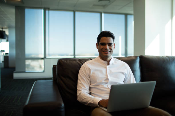 istock Businessman using laptop while sitting of sofa in office 676792786