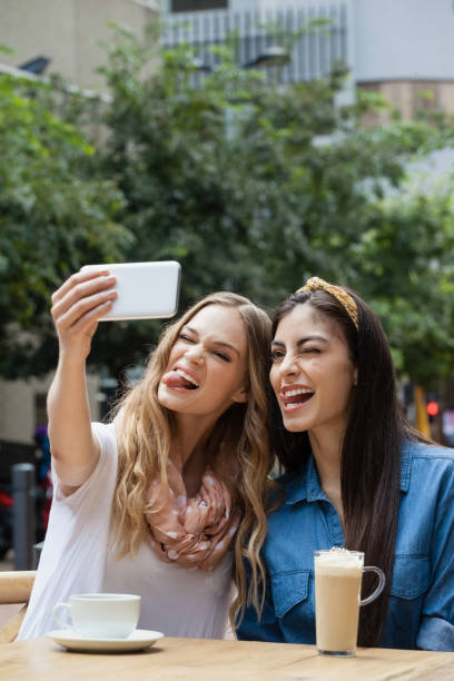 istock Cheerful friends photographing while sitting at sidewalk 676870034