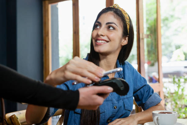 mujer sonriente haciendo pago a lector de tarjetas de crédito - e reader cheerful indoors lifestyles fotografías e imágenes de stock