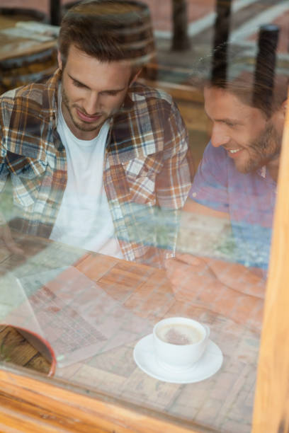 istock Friends using laptop while sitting by window at cafe shop 677025958