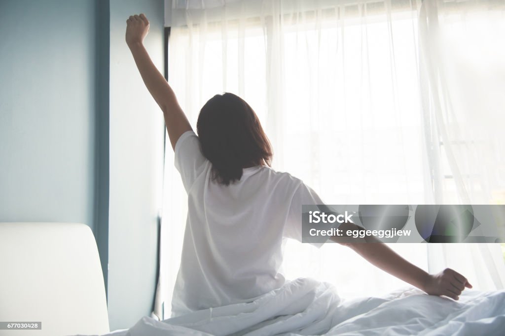 Asian woman waking up in the morning. Outstretched arms. Sleeping Stock Photo