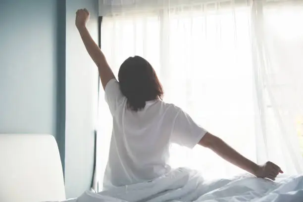 Photo of Asian woman waking up in the morning. Outstretched arms.