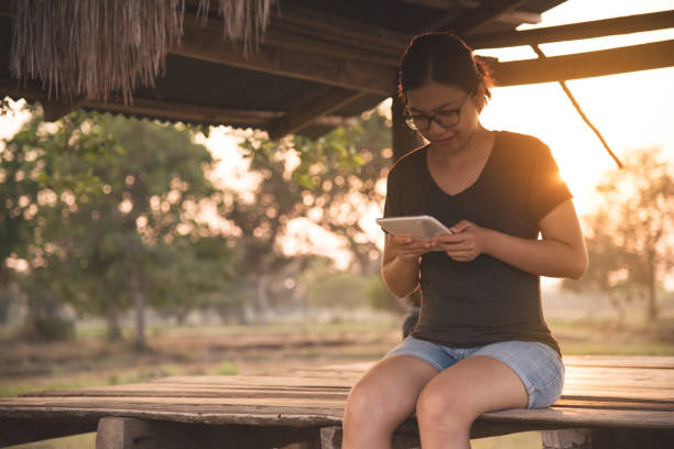 istock Asian girl using tablet or smartphone on countryside background. 677031336