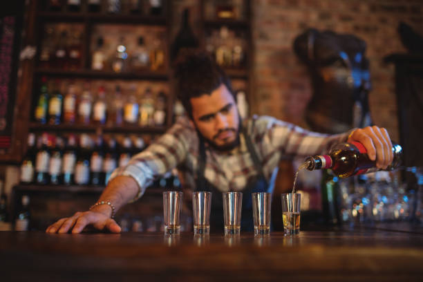 istock Waiter pouring tequila into shot glasses at counter 677045548
