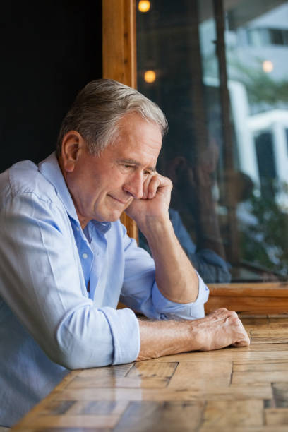 istock Thoughtful senior man looking away while sitting at table 677069750