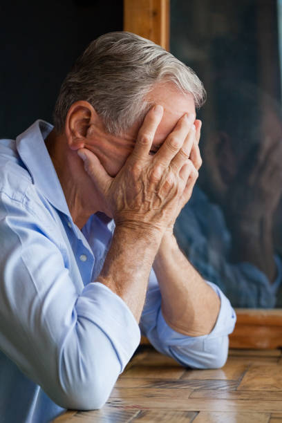 istock Close-up of senior man covering face while sitting at table 677069928