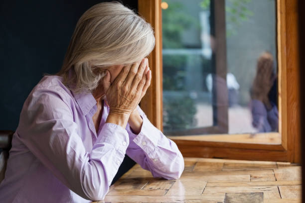 istock Senior woman covering face while sitting at table in cafe 677078282