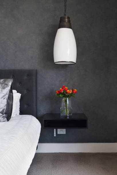 istock Orange roses on bedside table in contemporary dark bedroom 677115210