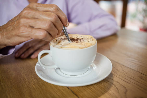 istock Close up of woman stirring coffee while sitting at table 677145866