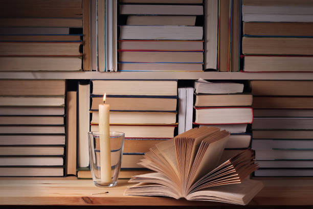 istock The opened book and the burning candle against from books. 677157176