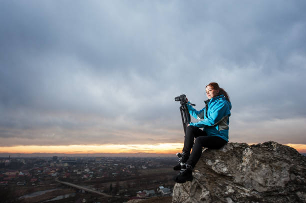 istock Female photographer with camera on tripod on the big rock 677181572