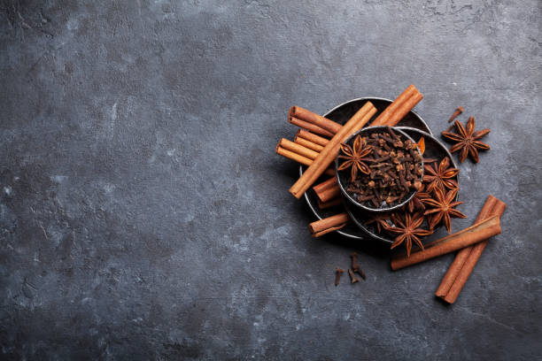 Various spices bowls over stone Various spices bowls over stone background. Cinnamon, anise, clove. Top view with copy space cinnamon sticks cloves stock pictures, royalty-free photos & images