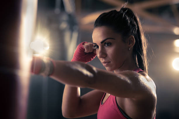 istock Young female boxer punching a bag during kickboxing training in a gym. 677290956