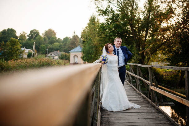 istock Cheerful wedding couple on wooden bridge at sunset. 677314344