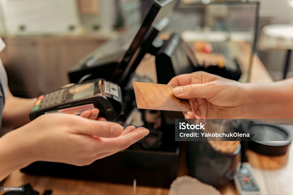 Customer buying food in shop Close up of female hand paying for purchase by credit card. Saleswoman is holding device Paying Stock Photo
