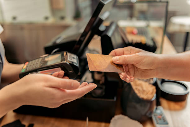 Customer buying food in shop Close up of female hand paying for purchase by credit card. Saleswoman is holding device commercial activity stock pictures, royalty-free photos & images