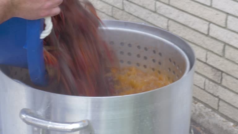 Man Dumps a Large Sack of Live Crawfish into a Metal Pot of Boiling Water