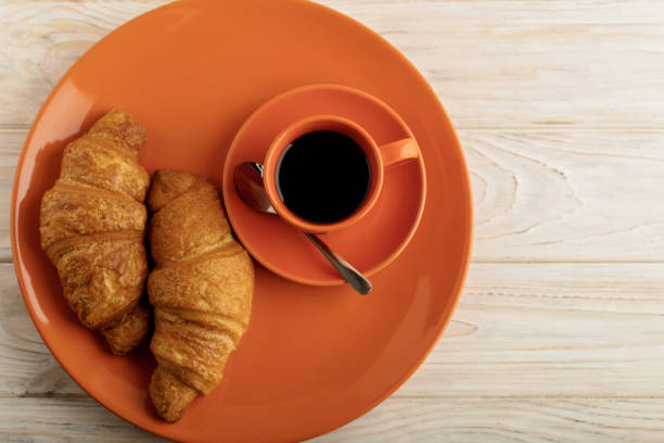 Coffee with croissants on a light wooden background. Selective focus.