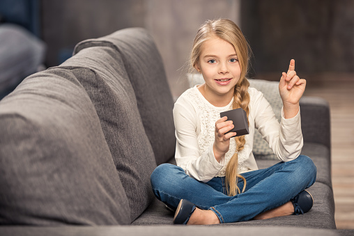 Cute little girl playing with cube and pointing up with finger