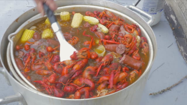 Man Stirs Pot of Boiling Crawfish with a Spatula