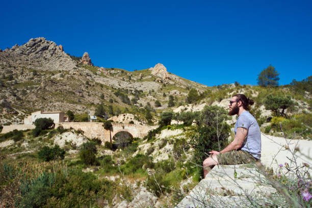 istock Bearded man traveler sitting on a edge 677424714