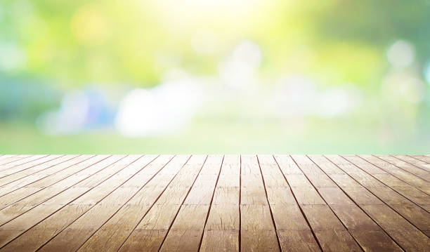 istock Empty wooden table with out of focus green park background . 677427926