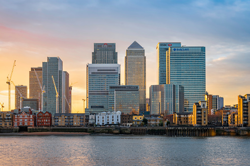 London, United Kingdom - December 22, 2016: View across river Thames to skyscrapers district Canary Wharf in London at sunset. Copy space in sky.
