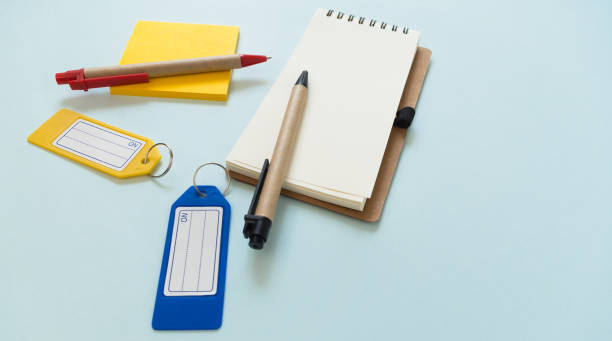 istock Notebook place on blue background with yellow post it, pens and plastic tags 677443042