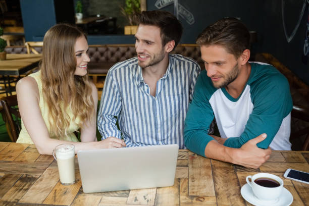 istock Happy friends looking at digital laptop while sitting by table 677443726