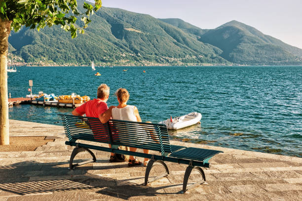 Ascona, Switzerland - August 23, 2016: Couple sitting on the bench at the promenade of the luxurious resort in Ascona on Lake Maggiore, Ticino canton, Switzerland.