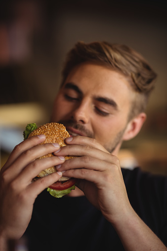 Close-up of man eating burger in restaurant